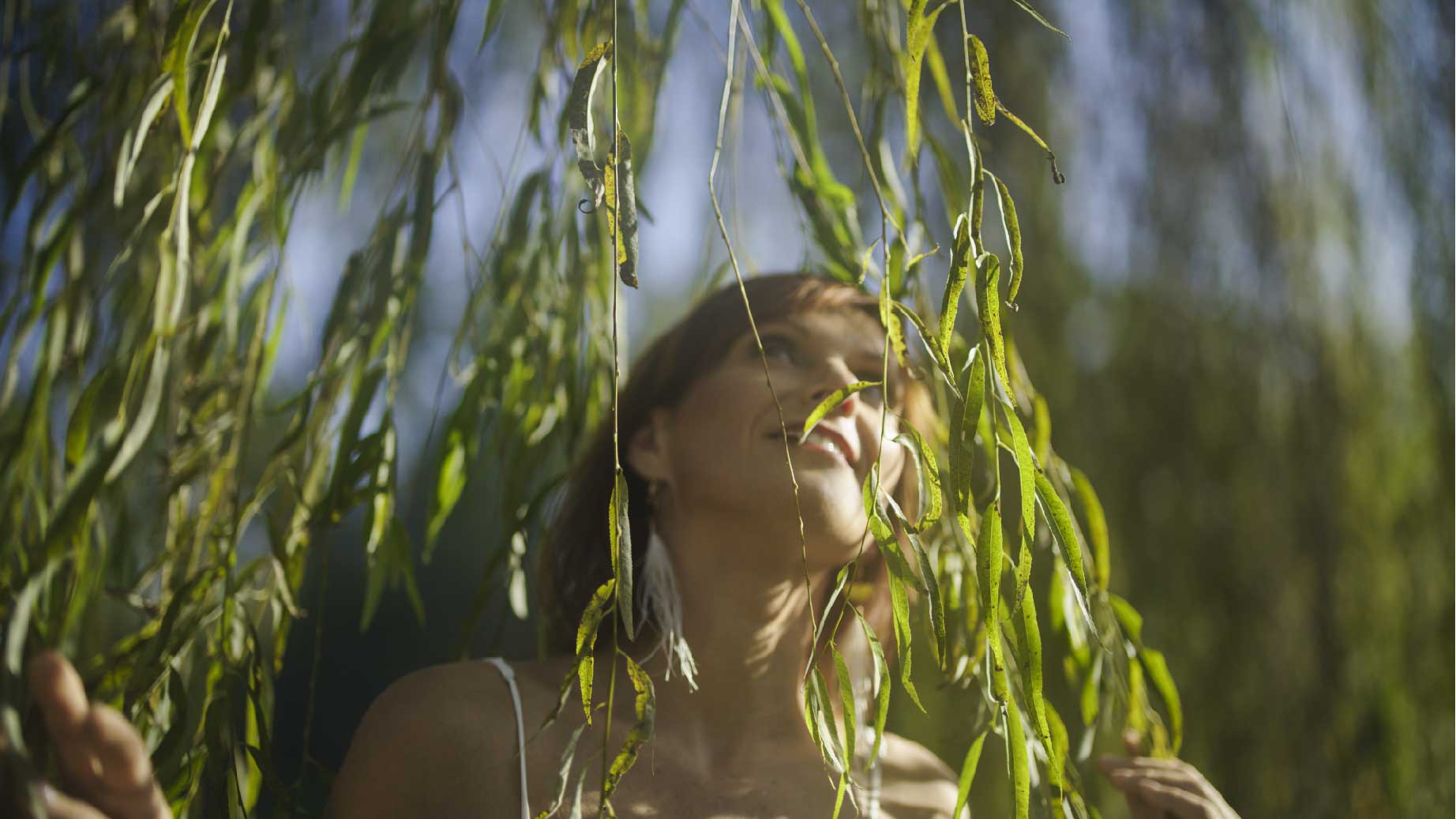 Praktijk Amura. Vrouw in de zon bij een wilg.